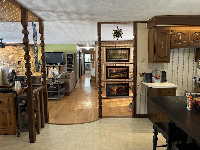 kitchen with a textured ceiling, dark brown cabinetry, and light hardwood / wood-style flooring