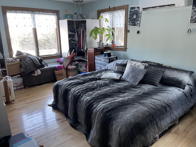 bedroom featuring light hardwood / wood-style flooring and an AC wall unit