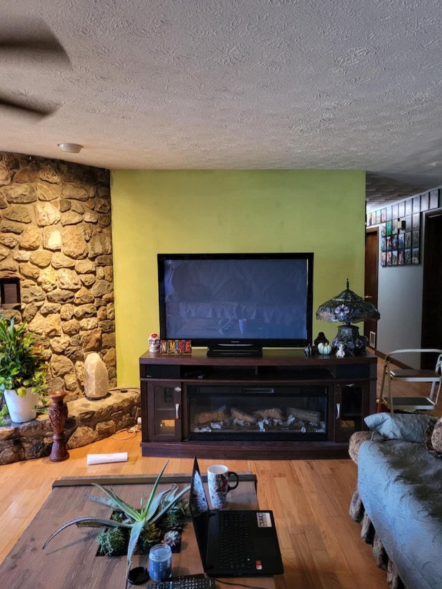 living room with a textured ceiling, a fireplace, and wood-type flooring