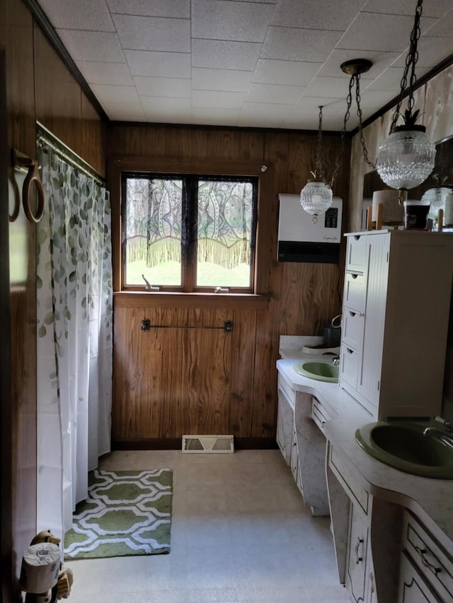 bathroom with a notable chandelier, sink, and wood walls