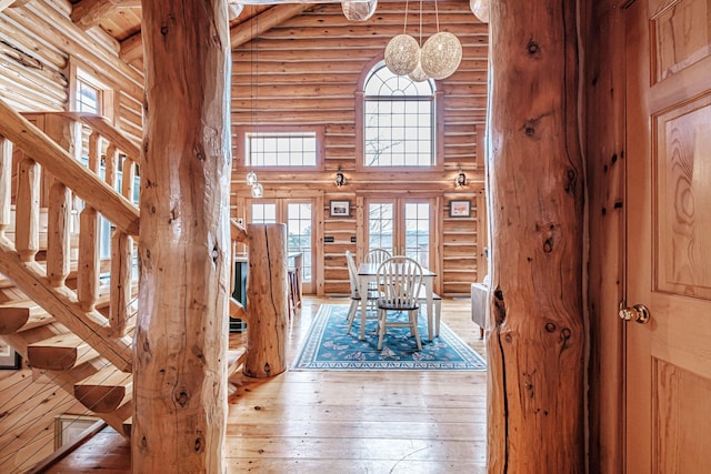 entrance foyer featuring beam ceiling, hardwood / wood-style flooring, a high ceiling, and log walls