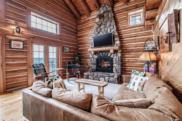 living room with light hardwood / wood-style floors, beam ceiling, rustic walls, a stone fireplace, and wooden ceiling