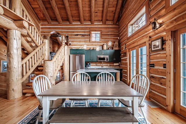 unfurnished dining area with light hardwood / wood-style floors, wooden ceiling, french doors, rustic walls, and beam ceiling