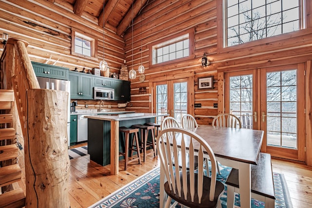 dining space featuring high vaulted ceiling, french doors, beamed ceiling, and light hardwood / wood-style flooring