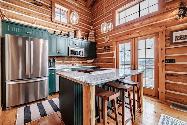 kitchen featuring appliances with stainless steel finishes, a kitchen island, hanging light fixtures, high vaulted ceiling, and light stone counters