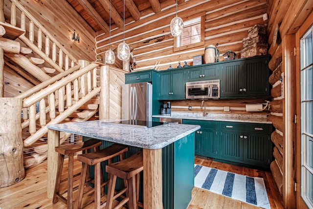 kitchen featuring a center island, beam ceiling, pendant lighting, appliances with stainless steel finishes, and log walls