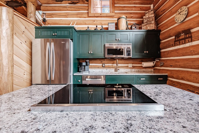 kitchen featuring light stone countertops, appliances with stainless steel finishes, log walls, sink, and green cabinets