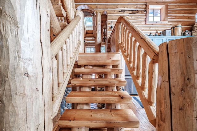 staircase with hardwood / wood-style flooring and rustic walls