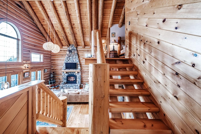 stairs featuring lofted ceiling with beams, wood-type flooring, a fireplace, and wooden ceiling