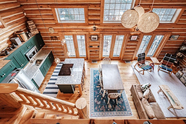 living room featuring a high ceiling, wood-type flooring, log walls, and french doors