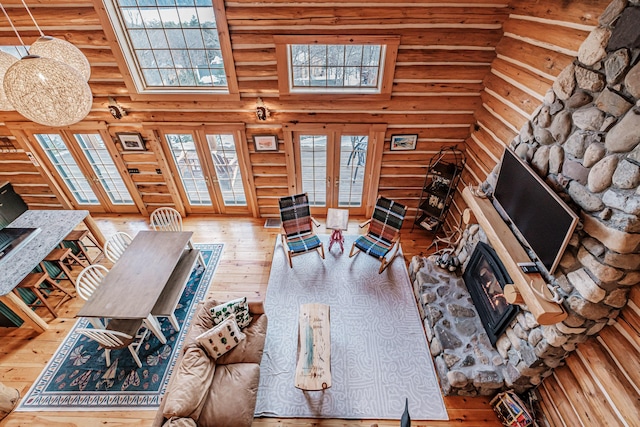 living room with hardwood / wood-style flooring, a high ceiling, log walls, a fireplace, and french doors