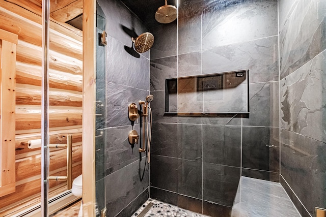 bathroom with toilet, a tile shower, and a baseboard radiator