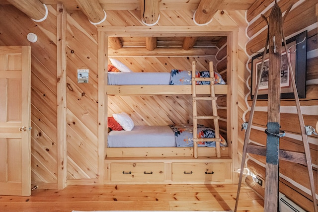 unfurnished bedroom featuring a baseboard heating unit, hardwood / wood-style flooring, and wooden walls