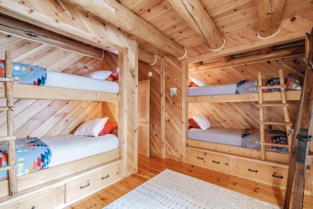 bedroom with wooden ceiling, beam ceiling, light hardwood / wood-style floors, and wood walls