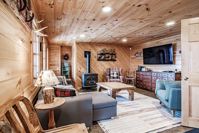 living room with wood ceiling, a wood stove, and wooden walls