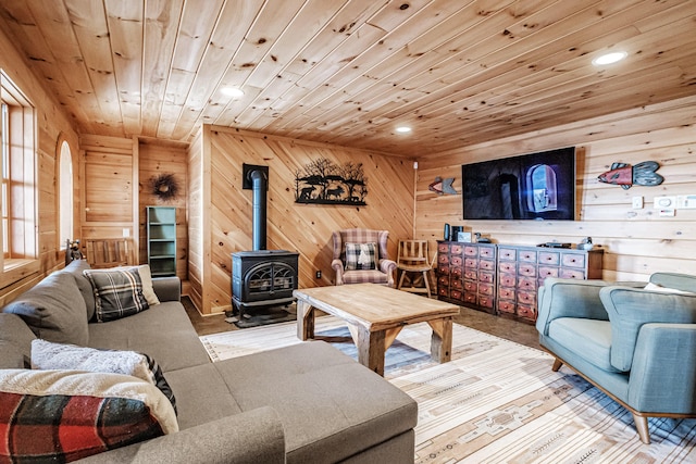 living room with wooden walls, a wood stove, and wooden ceiling