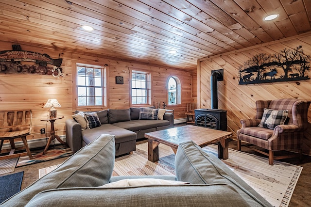 living room featuring light hardwood / wood-style floors, wood walls, a wood stove, and wooden ceiling