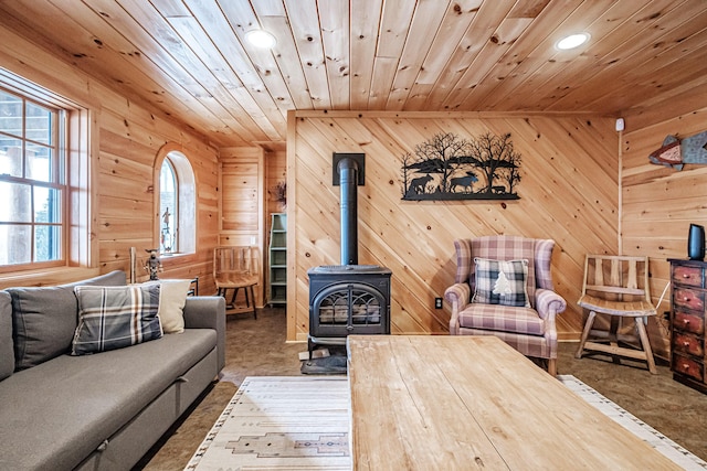 living room featuring a wood stove, wood ceiling, and wooden walls