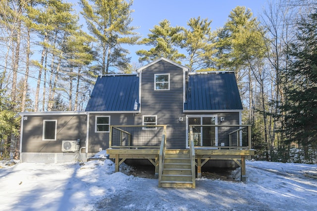 snow covered back of property with ac unit and a deck