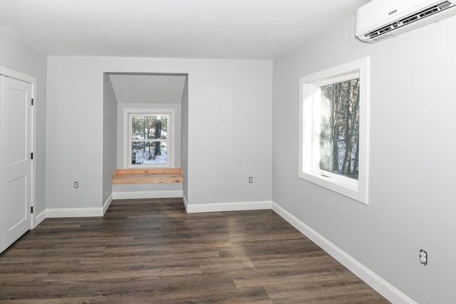 unfurnished room featuring a wall mounted AC and dark hardwood / wood-style flooring