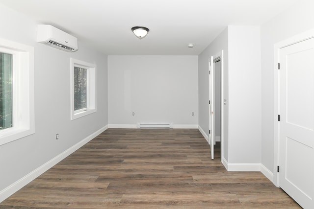 spare room featuring baseboard heating, dark hardwood / wood-style floors, and an AC wall unit