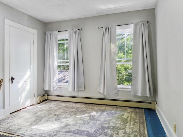 unfurnished room featuring baseboard heating and a healthy amount of sunlight