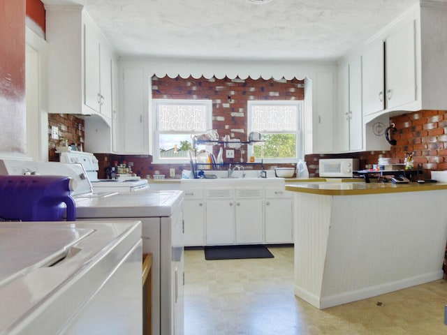 kitchen featuring washer / dryer, tile counters, backsplash, and white cabinets