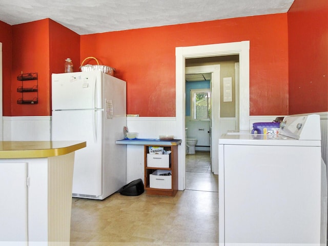 kitchen with a textured ceiling, white refrigerator, and washer / dryer