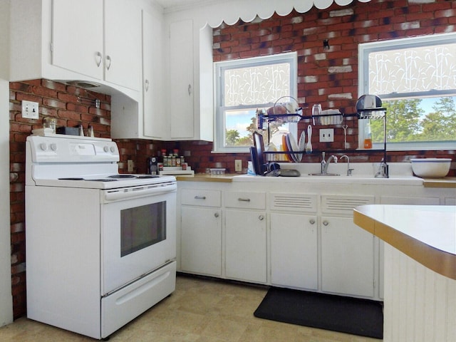 kitchen featuring white electric range oven and white cabinetry