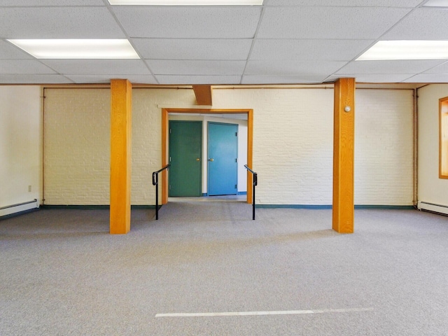 basement featuring light colored carpet, brick wall, and a baseboard heating unit