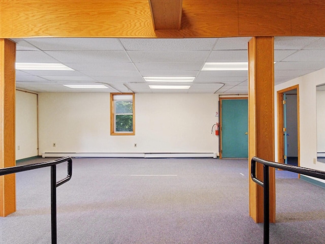 basement with a baseboard heating unit, a paneled ceiling, and carpet flooring