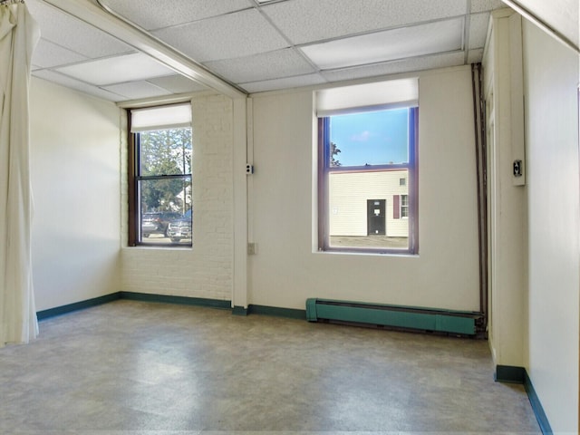 unfurnished room with a paneled ceiling and a baseboard heating unit