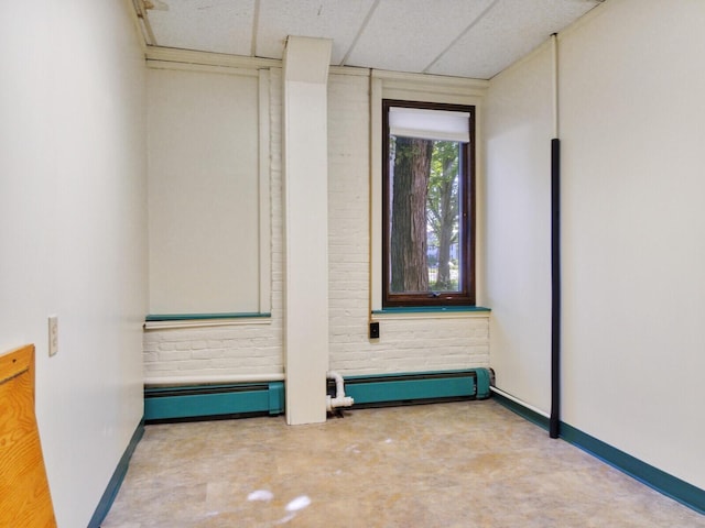 empty room featuring baseboard heating and a drop ceiling