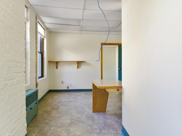 interior space with brick wall and a drop ceiling