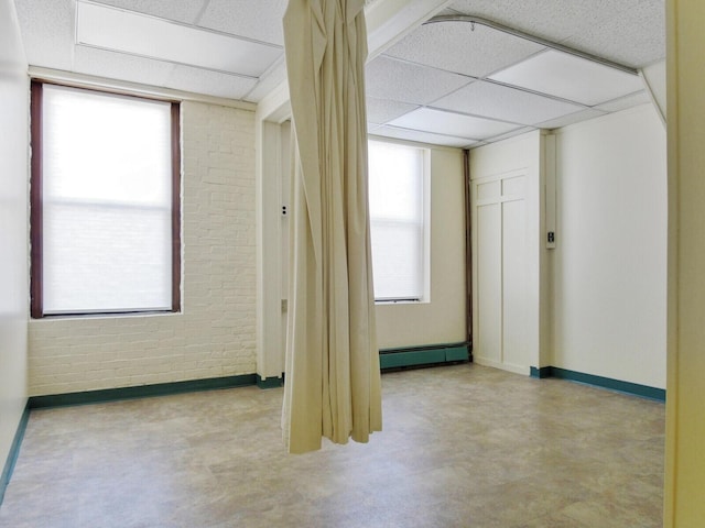 empty room with brick wall and a drop ceiling