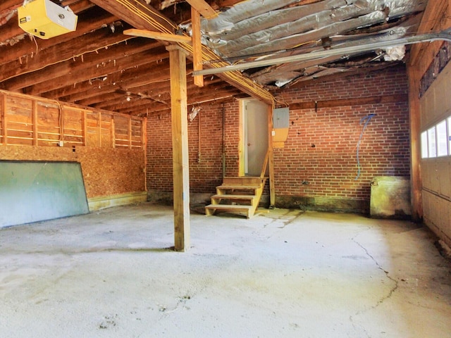 misc room with brick wall, concrete floors, and electric panel