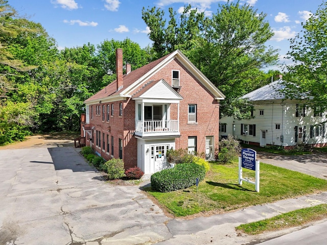 view of front property featuring a balcony and a front lawn