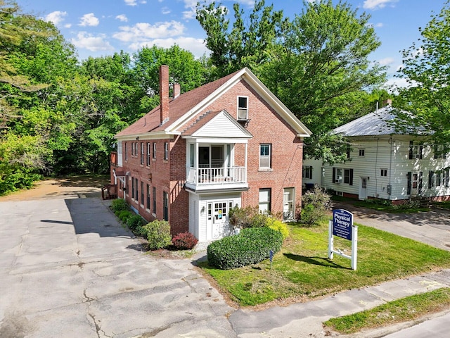 view of front facade with a balcony and a front lawn