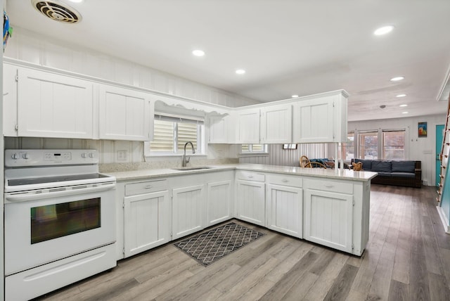 kitchen featuring light wood-type flooring, white cabinets, white electric range oven, and sink