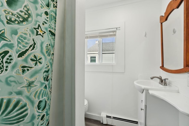 bathroom with a baseboard heating unit, toilet, vanity, and curtained shower