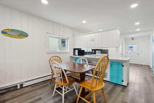 dining area with a healthy amount of sunlight, baseboard heating, and dark wood-type flooring