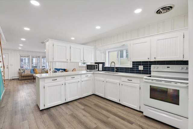 kitchen with electric stove, kitchen peninsula, and white cabinetry