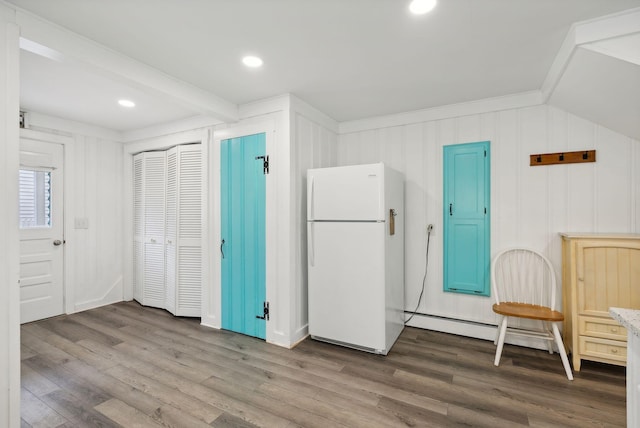 interior space with beamed ceiling, white refrigerator, ornamental molding, and hardwood / wood-style flooring