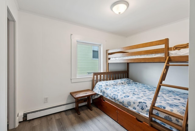 bedroom with wood-type flooring, a baseboard heating unit, and crown molding