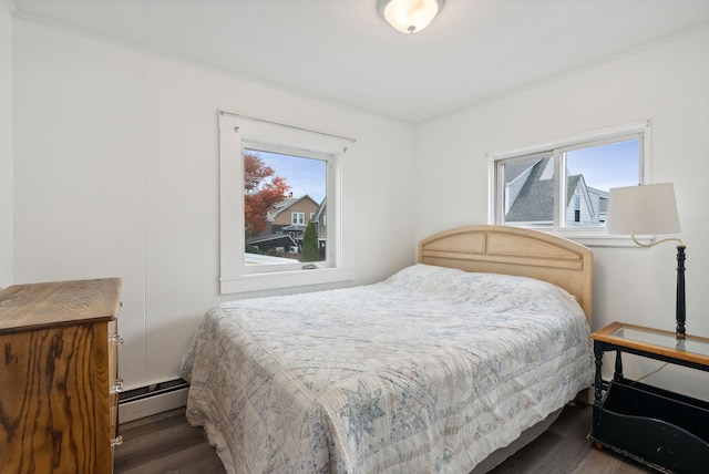 bedroom featuring multiple windows, a baseboard heating unit, and dark hardwood / wood-style floors