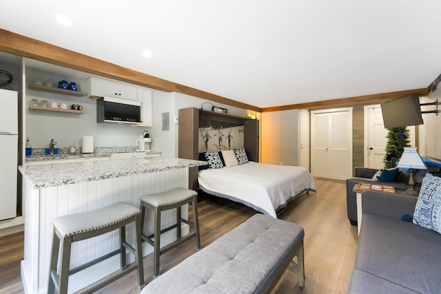 bedroom with wood-type flooring, a closet, and white fridge