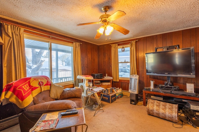 carpeted living room with ceiling fan, a wealth of natural light, ornamental molding, and wood walls