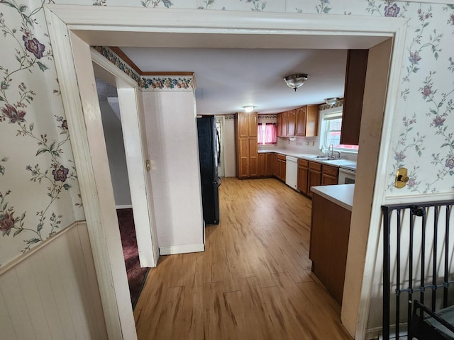 kitchen with black refrigerator, sink, light hardwood / wood-style flooring, and dishwasher