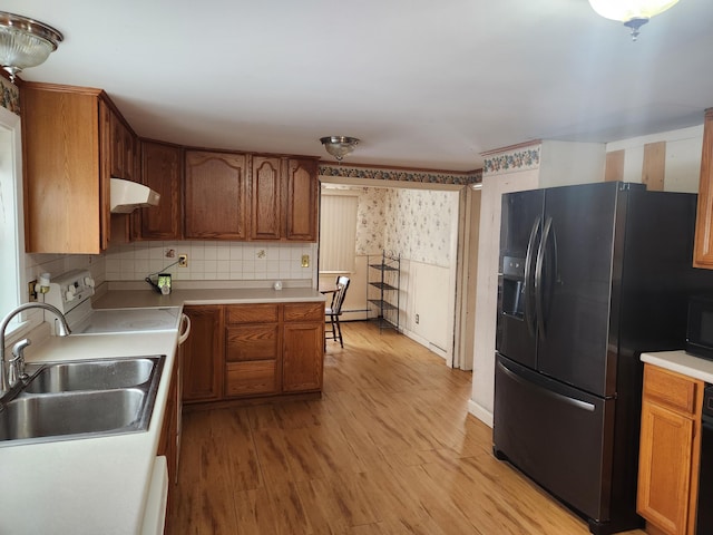 kitchen featuring electric range oven, tasteful backsplash, sink, fridge with ice dispenser, and light wood-type flooring