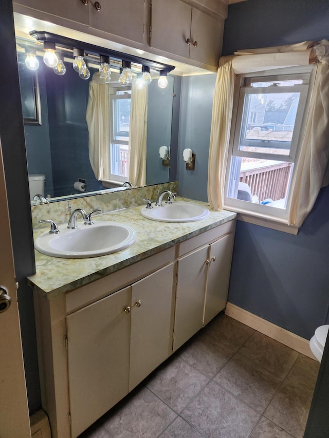 bathroom featuring vanity, plenty of natural light, tile patterned floors, and toilet